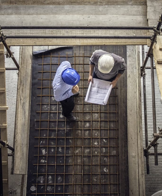 Deux hommes sur un chantier qui consulte un plan